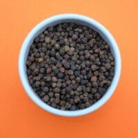 Photo by Nancy Hughes a bowl of black pepper on an orange background